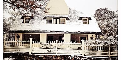 Snow-covered house with white picket fence on a winter day.