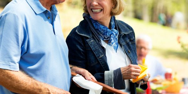 Smiling elderly couple enjoying a sunny outdoor meal together.