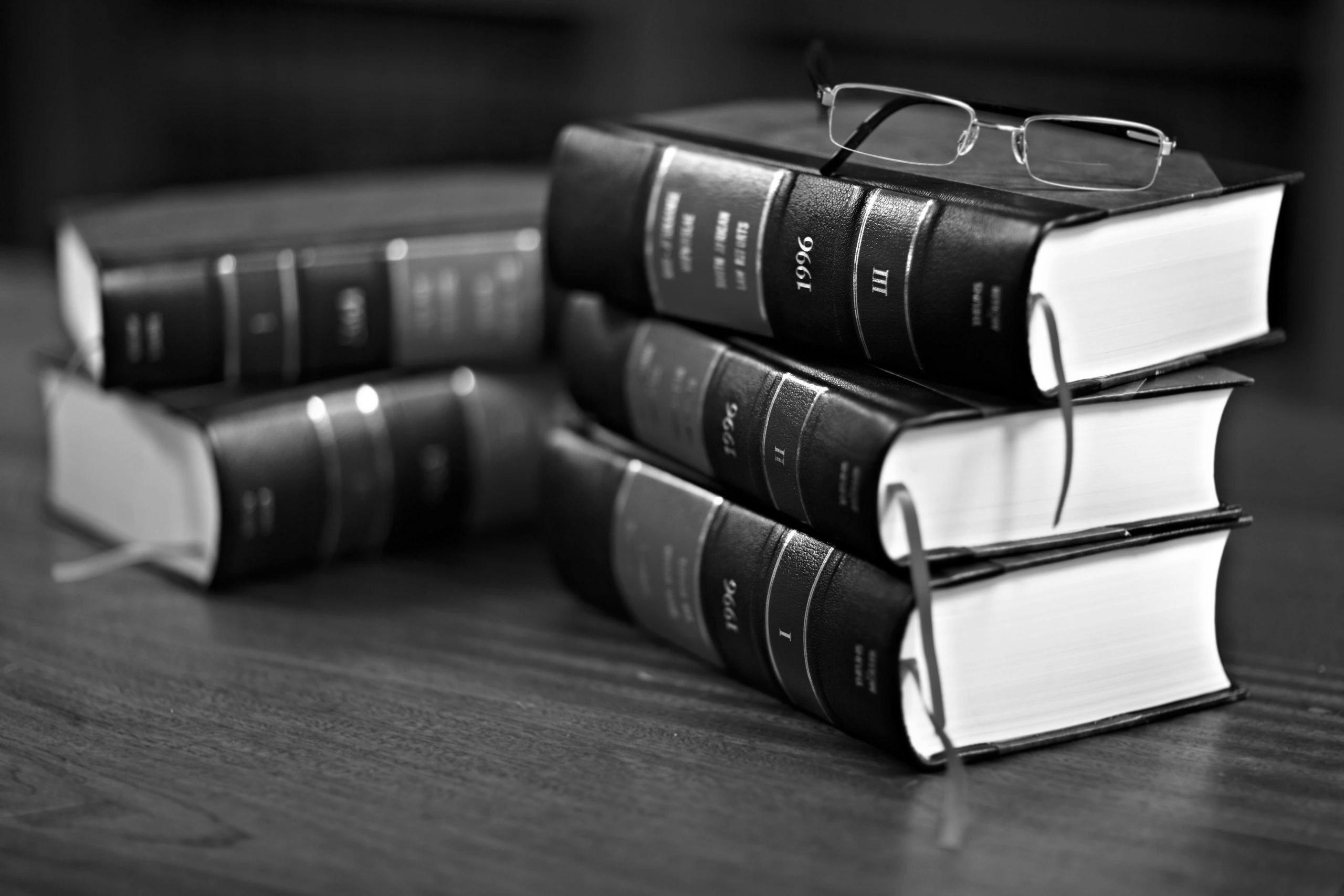 Stack of thick legal books with a pair of glasses on top.