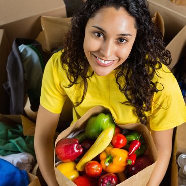 Woman smiling with a bag full of fresh vegetables.