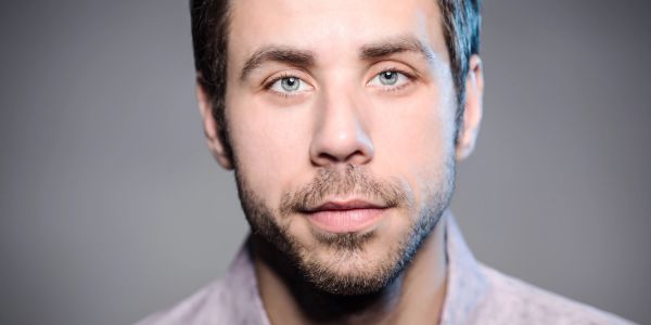 Close-up of a young man with blue eyes and beard.