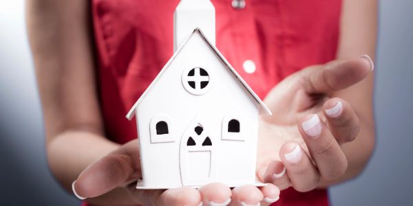 Person holding a small white model house.