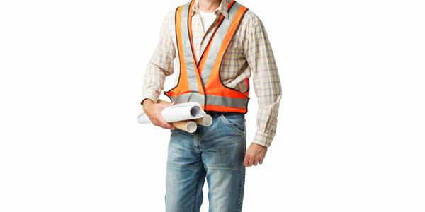 Smiling construction worker wearing a hard hat and safety vest holding blueprints.