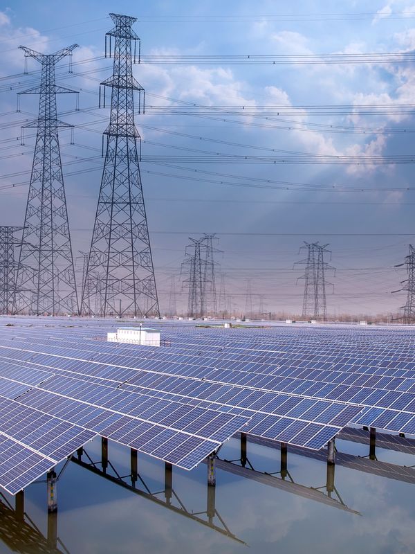 Solar panels on water with power transmission towers in the background.