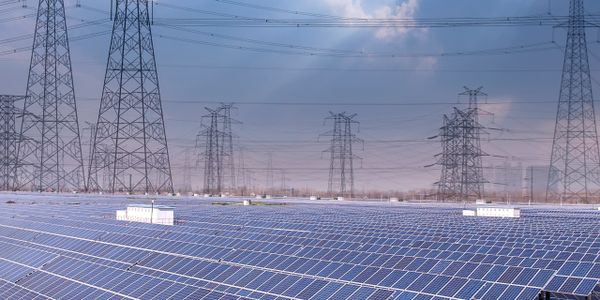 Solar panels floating on water with power transmission towers in the background.