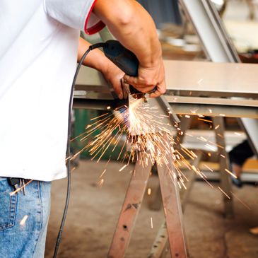 Worker using a grinder on metal, sparks flying.