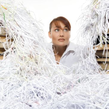 Woman surrounded by shredded paper.