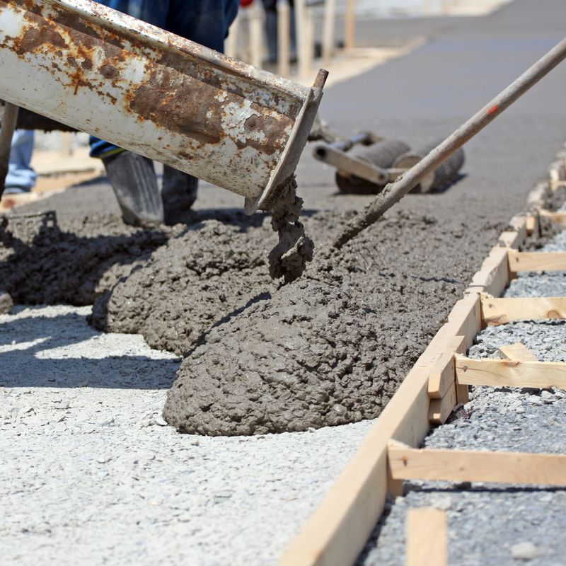 Freshly poured concrete is raked and leveled on a new sidewalk construction project. Shallow dof with focus on image centre.