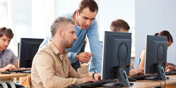 Teacher helping a student in a computer lab.