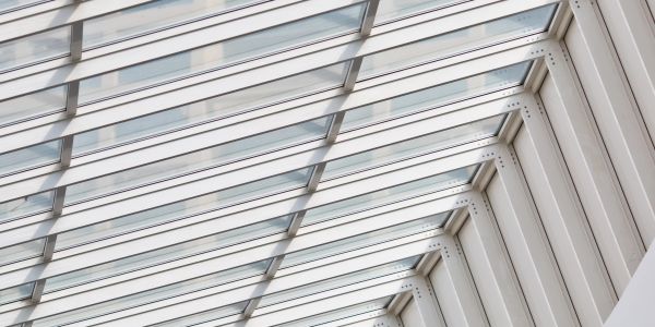 Modern glass and metal ceiling structure with angled beams.