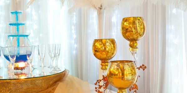 Elegant golden goblets and blue champagne fountain on a decorated table.