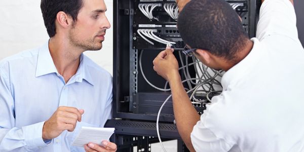 Two men working on server cables in a data center.