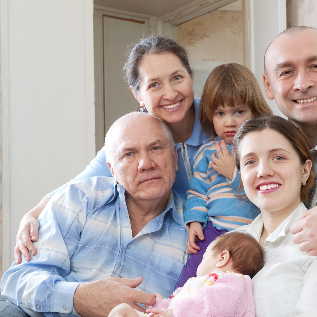 A happy multi-generational family posing together indoors.