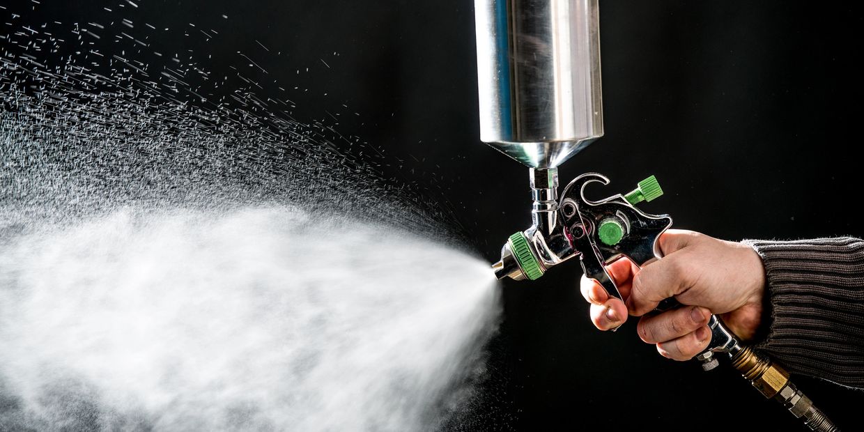 Hand spraying paint with spray gun.