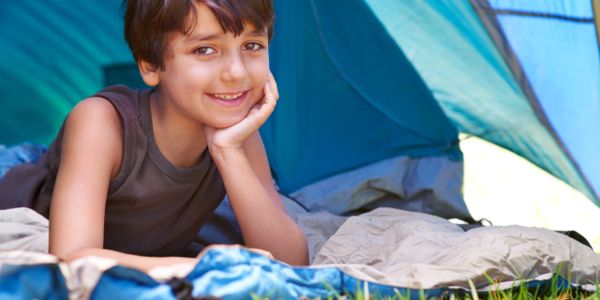 Smiling boy lying inside a tent on a camping trip.