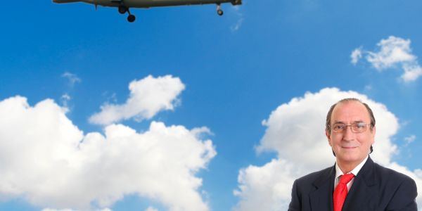 Man in suit with airplane flying against a blue sky with clouds.