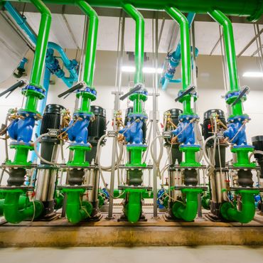 Industrial green and blue piping system with valves and motors.