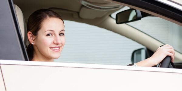 Smiling woman sitting in the driver's seat of a car.