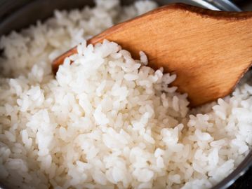 Close-up of cooked white rice with a wooden spatula.