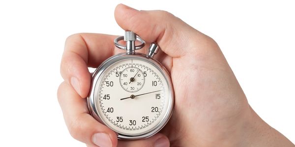 Hand holding a silver stopwatch against a white background.