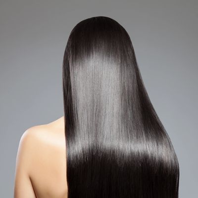 Long, straight, shiny, jet-black hair seen from the back. Bare shoulder against grey background.