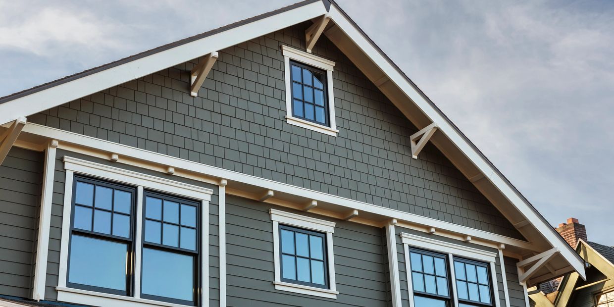 Close-up of a modern house facade with gray siding and white-trimmed windows.