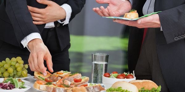 People in suits enjoying a variety of appetizers and refreshments at a social event.