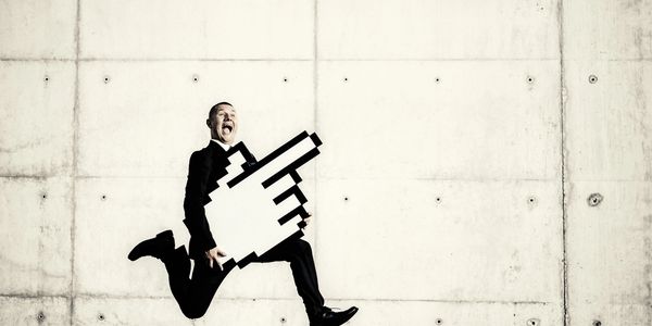 Man in suit joyfully jumping with a giant pixelated cursor hand.