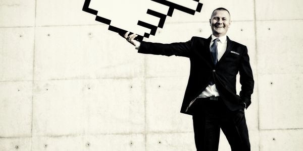 Man in suit holding a large pixelated cursor.