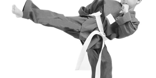 Child in blue martial arts uniform performing a high kick.
