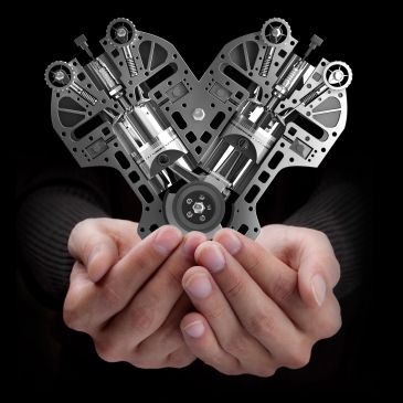 Hands holding a mechanical V-shaped engine model.