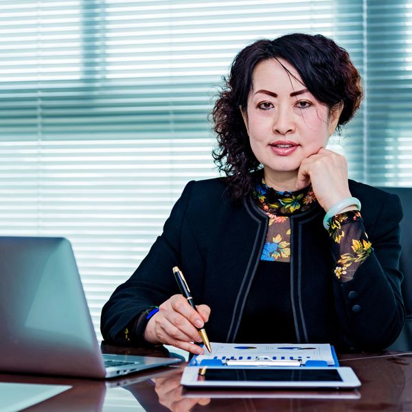 Professional woman analyzing charts at her desk with laptop and tablet.
