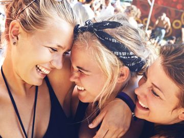 Three friends sharing a joyful moment together outdoors.