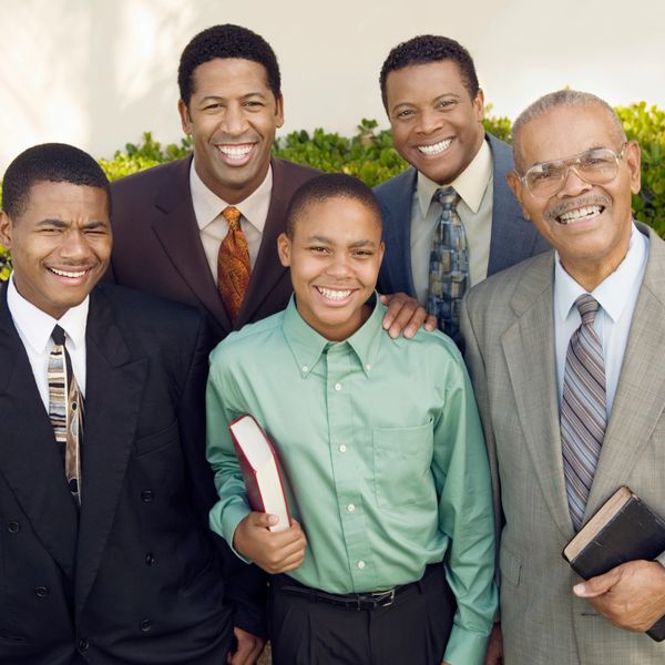 A happy multigenerational group of men smiling, some holding books.