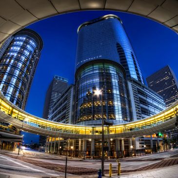 Urban cityscape with modern skyscrapers and a circular elevated walkway at dusk.