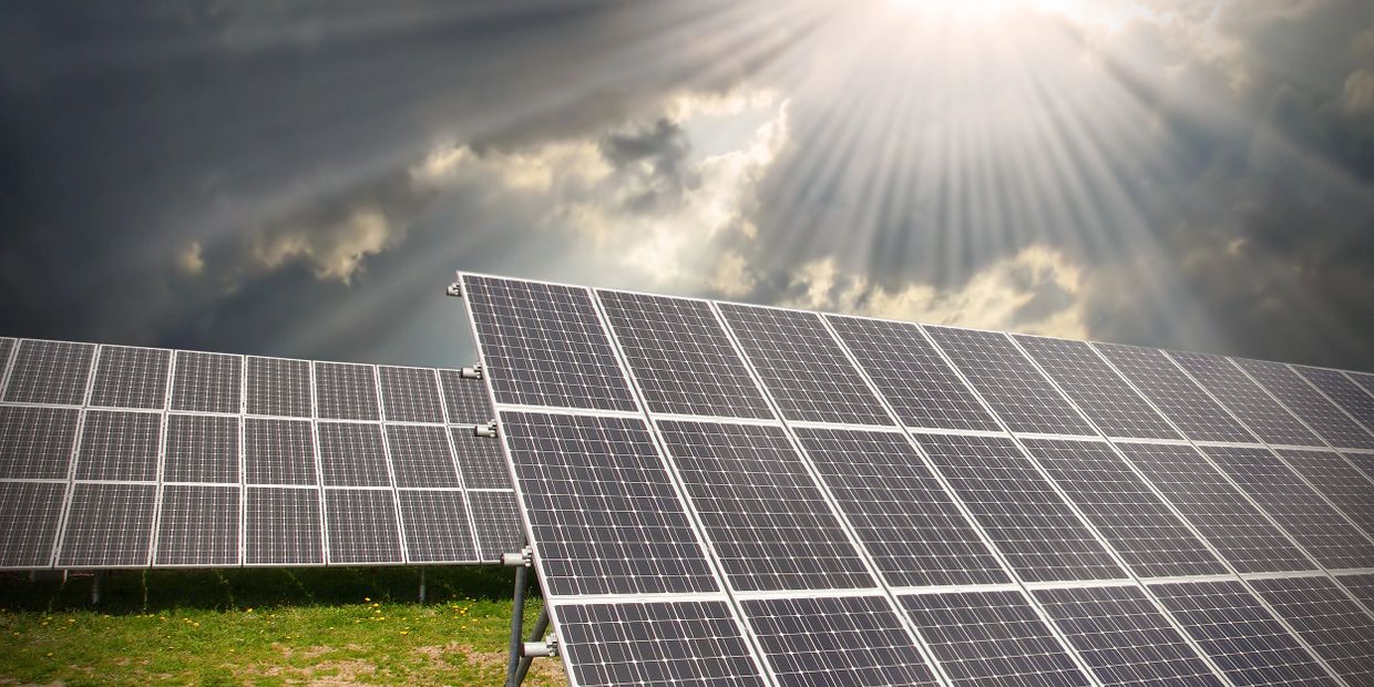 Solar panels under dramatic sunlight breaking through clouds.