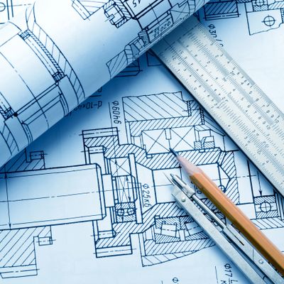Technical blueprints with drafting tools including pencil, compass, and ruler.