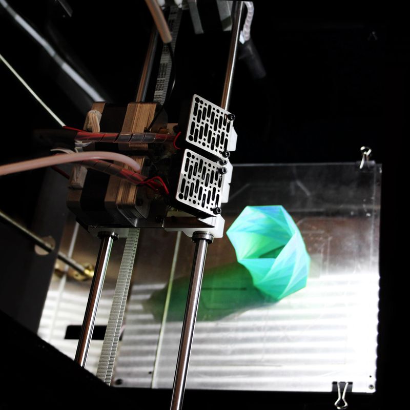 High angle view of a three dimensional printer, printing a green plastic container.