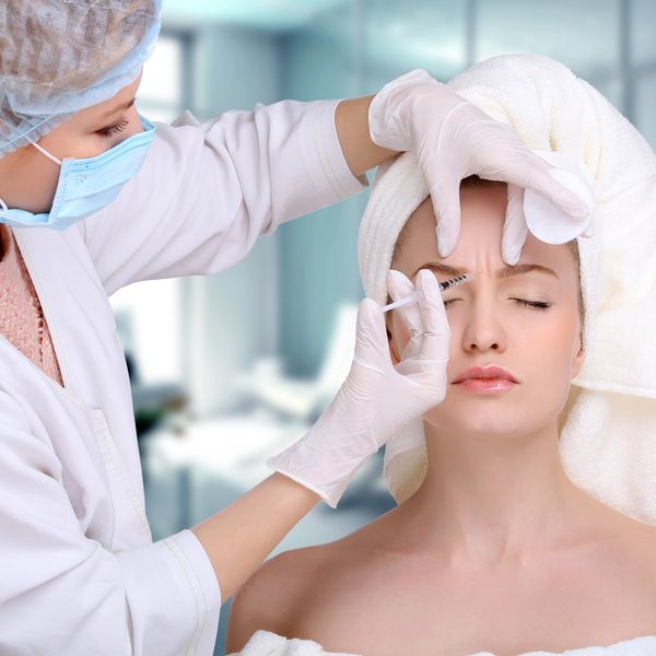 A woman receiving a cosmetic injection in her forehead by a professional.