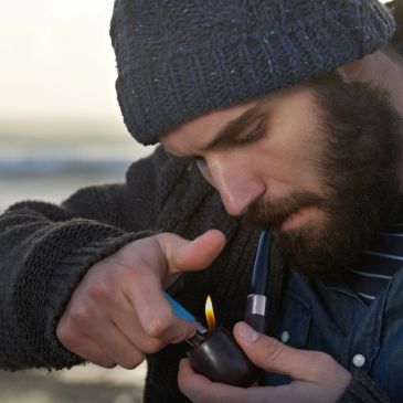 Man lighting a pipe with a lighter.