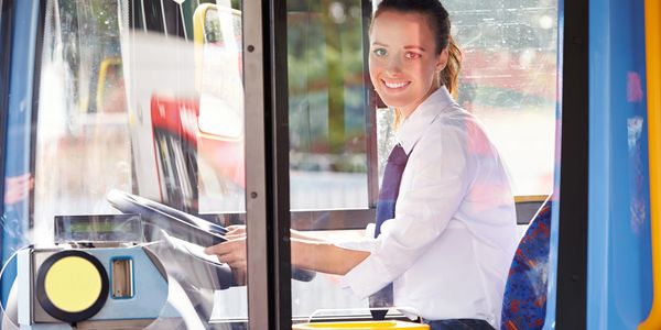 Smiling female bus driver behind the wheel.