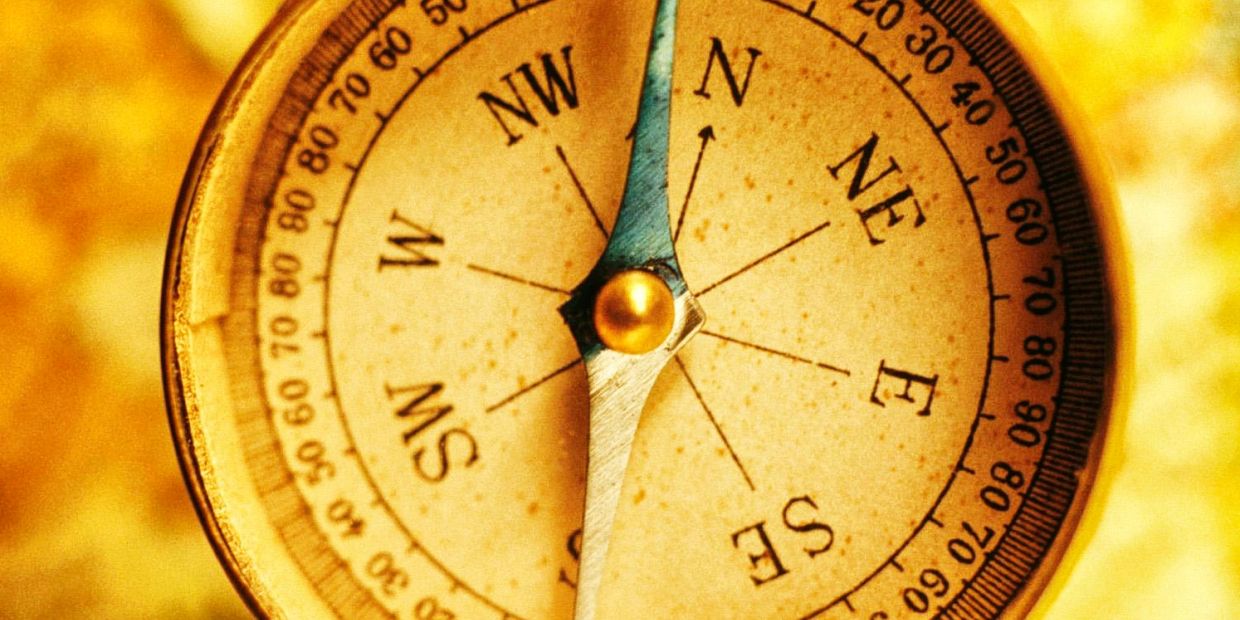 Close-up of an antique compass with a golden background.