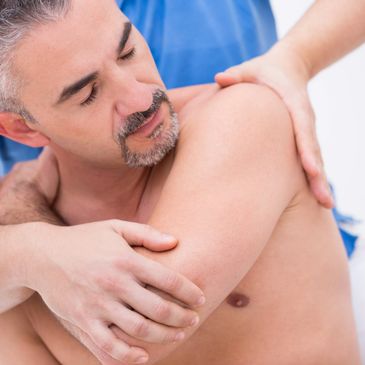 A man receiving a shoulder massage from a therapist.