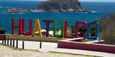Colorful HUATULCO sign overlooking the ocean.