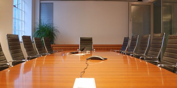 Modern conference room with a large wooden table and sleek black chairs.