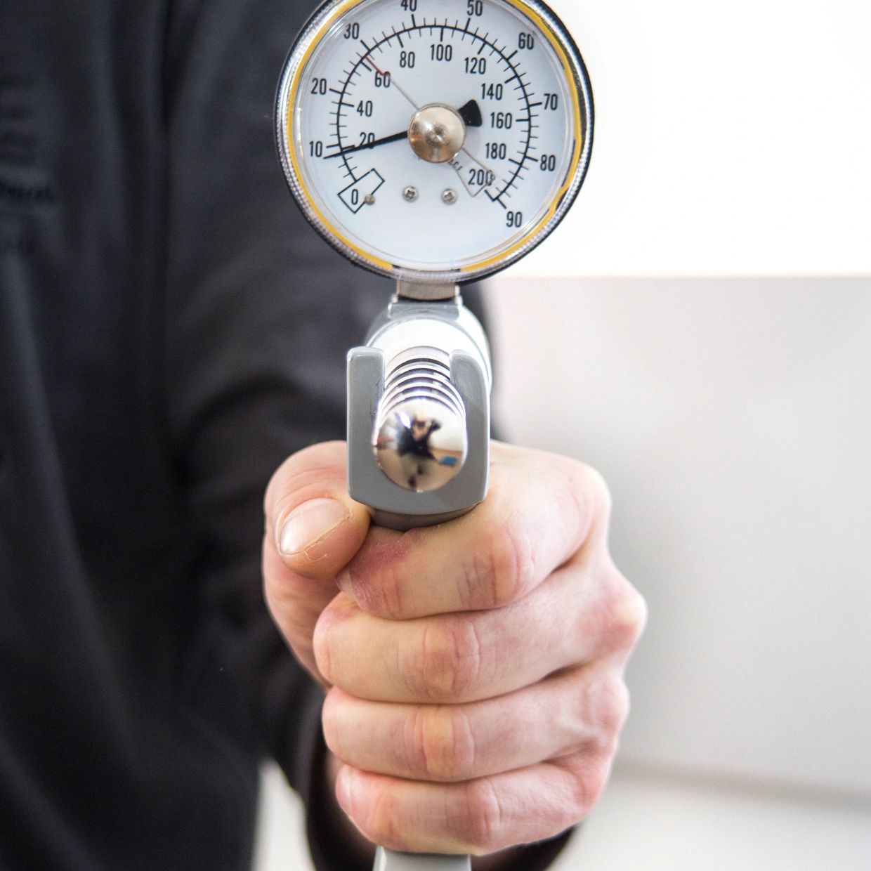 Hand holding a pressure gauge tool.