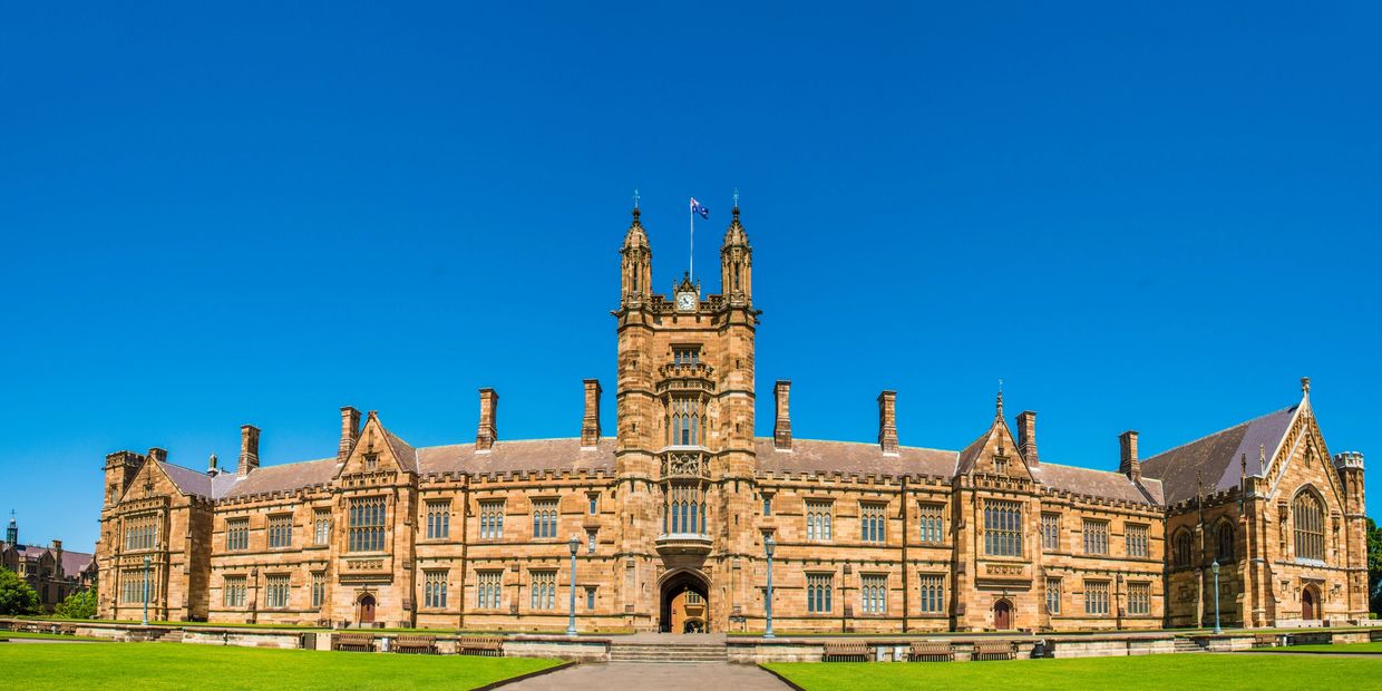 Historic university building with clock tower and flags.