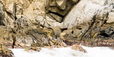 Rocky coastal cliff with waves crashing below.