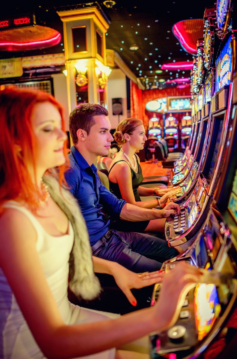 Three young people playing slot machines in a Casino.