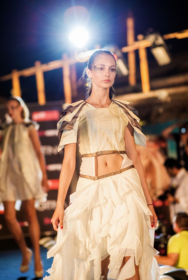 Young female fashion model wearing haute couture on the catwalk of a night fashion show.